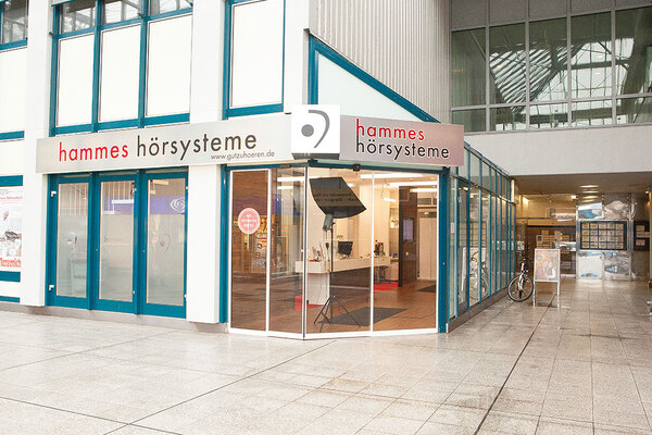 Das Geschäft Hammes Hörsysteme mit modernem Ladeneingang in einer Einkaufspassage.