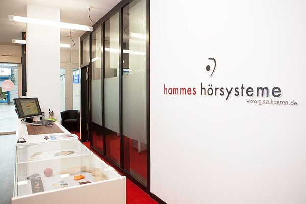 Modernes Hörakustik-Fachgeschäft mit Empfangstresen und hammes hörsysteme Logo.